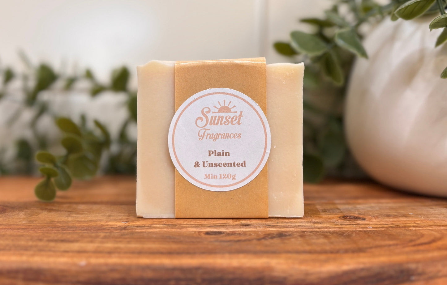 Bar of soap with a label on a wooden surface with plants in the background