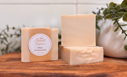 Three bars of soap on a wooden surface with a plant in the background
