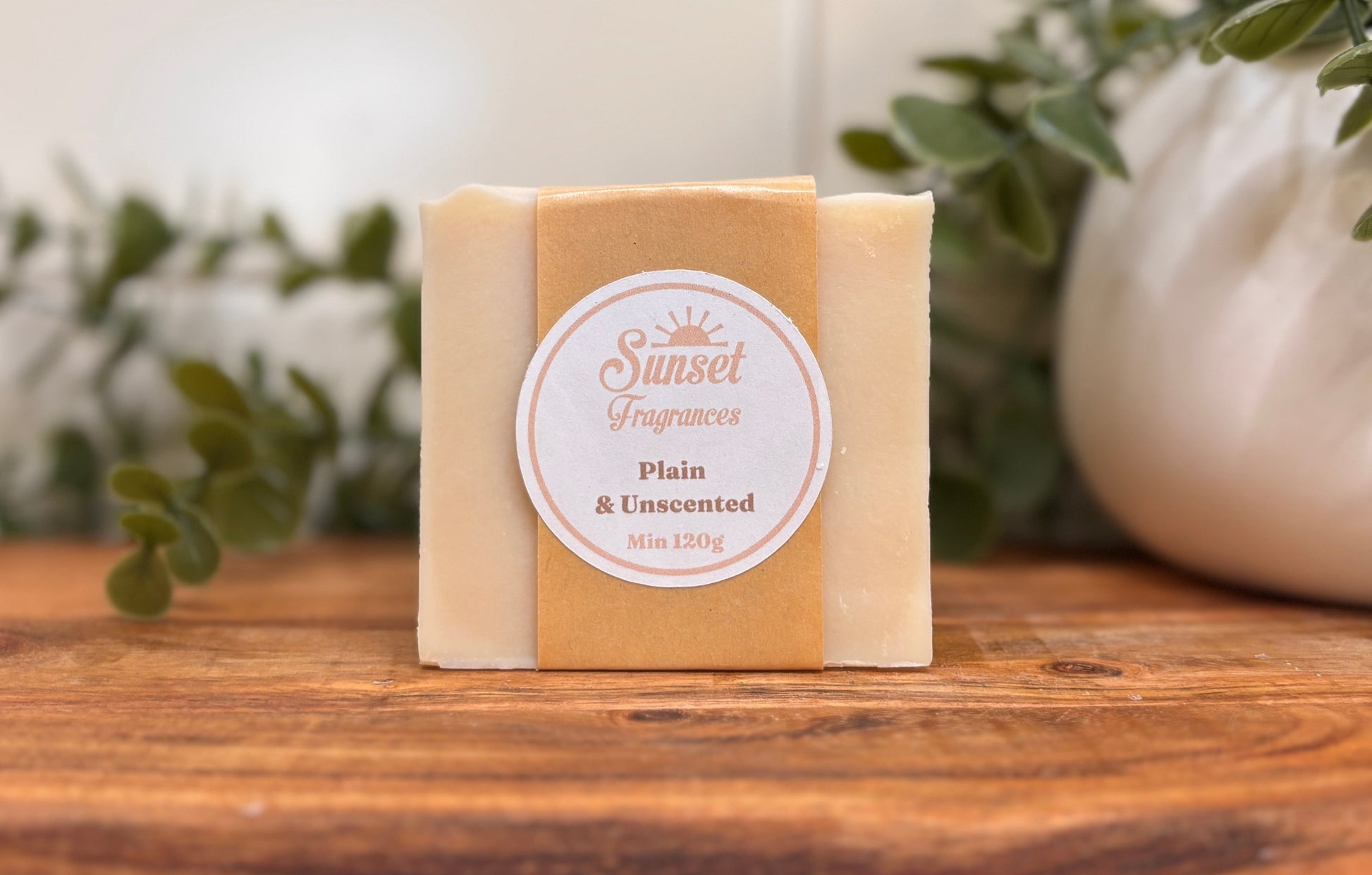 Bar of soap with a label on a wooden surface with plants in the background
