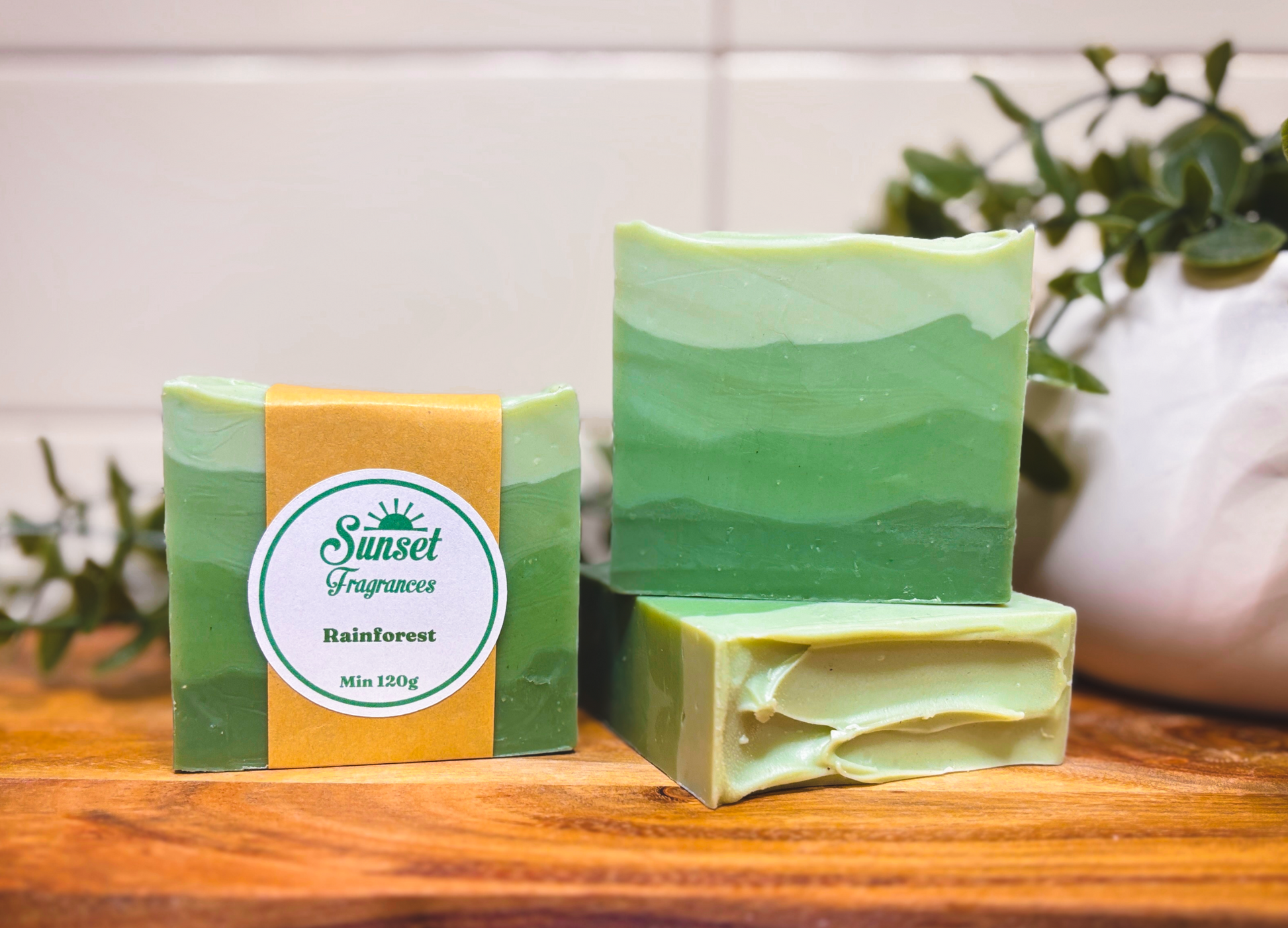 Green soap bars with a box on a wooden surface, featuring 'Sunset' branding.